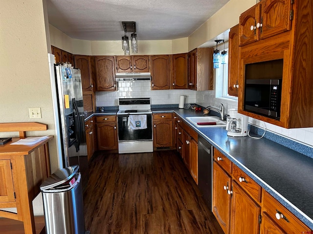 kitchen featuring sink, a textured ceiling, stainless steel appliances, decorative backsplash, and dark hardwood / wood-style floors