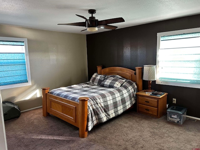 bedroom with multiple windows, a textured ceiling, dark carpet, and ceiling fan