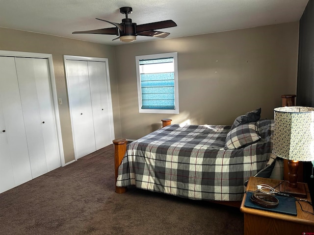 carpeted bedroom featuring multiple closets, a textured ceiling, and ceiling fan