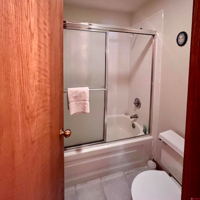 bathroom featuring shower / bath combination with glass door, toilet, and tile patterned flooring