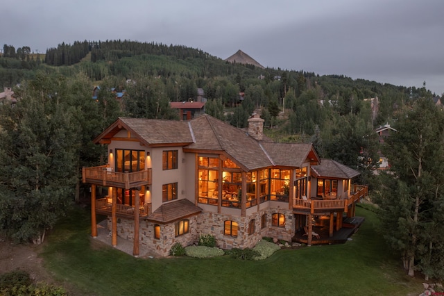 back of property featuring a balcony and a yard