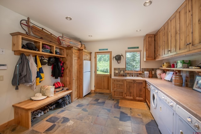 kitchen featuring tasteful backsplash, washing machine and clothes dryer, tile counters, white fridge, and sink