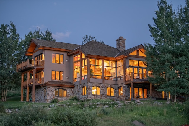 back house at dusk featuring a balcony