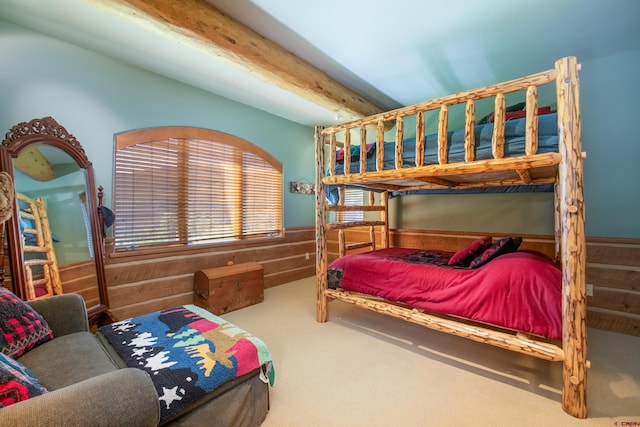 bedroom with beamed ceiling, carpet flooring, and wood walls