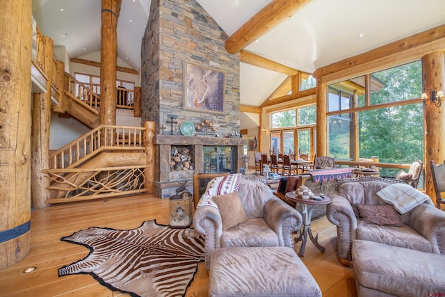 living room featuring a stone fireplace, beam ceiling, hardwood / wood-style flooring, and high vaulted ceiling