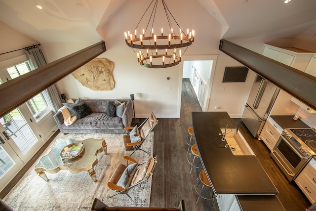 living room featuring lofted ceiling, dark wood-type flooring, and an inviting chandelier