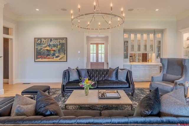 living room with crown molding, light hardwood / wood-style flooring, a notable chandelier, and bar