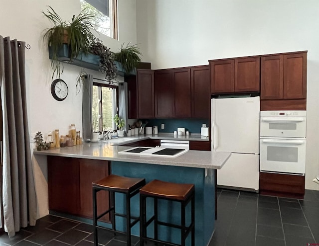 1660 Lake Purgatory Dr, Durango, CO 81301 - kitchen with white appliances, light countertops, a breakfast bar area, a peninsula, and dark tile patterned flooring