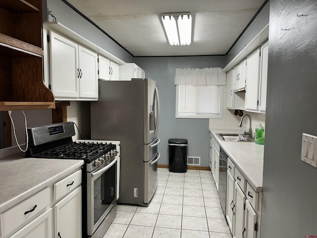 kitchen featuring tasteful backsplash, stainless steel appliances, sink, light tile patterned floors, and white cabinets