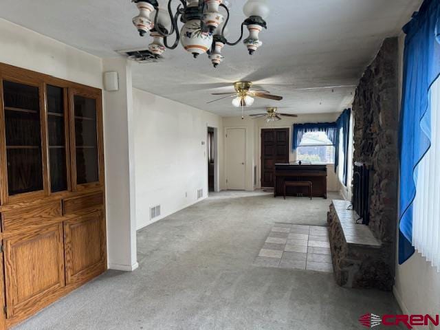 unfurnished living room featuring ceiling fan with notable chandelier and light carpet