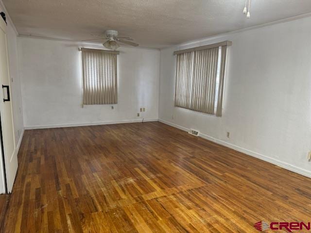 empty room featuring a textured ceiling, ceiling fan, and dark wood-type flooring