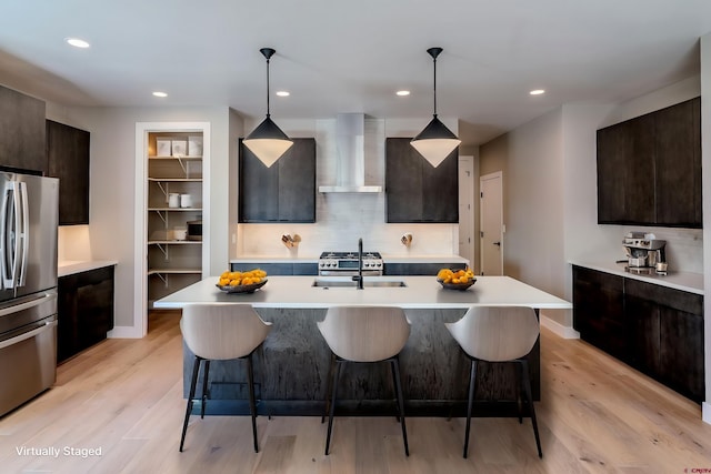 538 Hermosa Meadows Rd, Durango, CO 81301 - kitchen with wall chimney exhaust hood, stainless steel appliances, light countertops, a breakfast bar area, and a sink