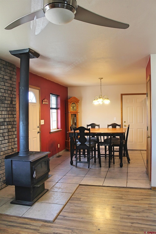 dining space featuring light wood-type flooring, an inviting chandelier, and a wood stove