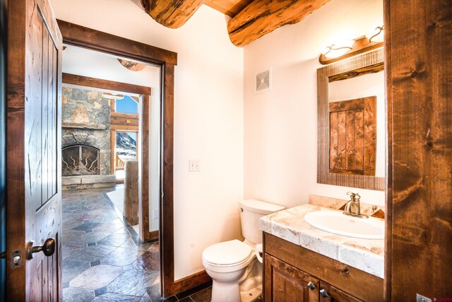 bathroom featuring vanity, a stone fireplace, and toilet