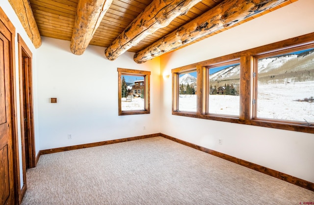 spare room featuring beam ceiling, wooden ceiling, and carpet