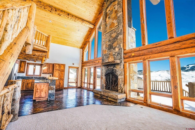 unfurnished living room with beam ceiling, a stone fireplace, high vaulted ceiling, and plenty of natural light