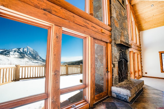 doorway featuring a mountain view, a stone fireplace, vaulted ceiling, and wood ceiling