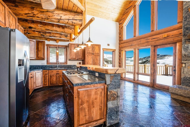 kitchen with hanging light fixtures, beamed ceiling, stainless steel appliances, sink, and a center island