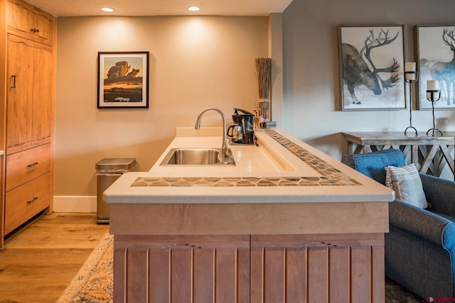 kitchen featuring light brown cabinets, kitchen peninsula, light hardwood / wood-style floors, and sink