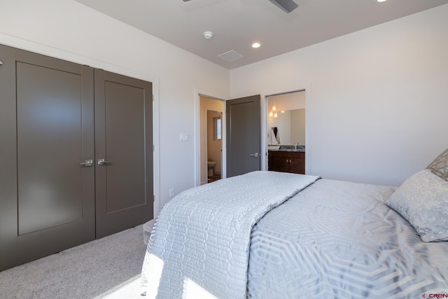 carpeted bedroom featuring ensuite bath, ceiling fan, and a closet