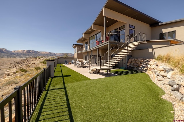 rear view of property featuring a mountain view, a lawn, and a patio