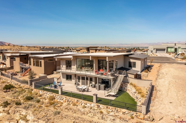 back of property with an outdoor living space, a patio, and a balcony