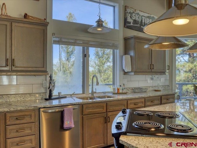 kitchen featuring appliances with stainless steel finishes, light stone countertops, hanging light fixtures, decorative backsplash, and sink