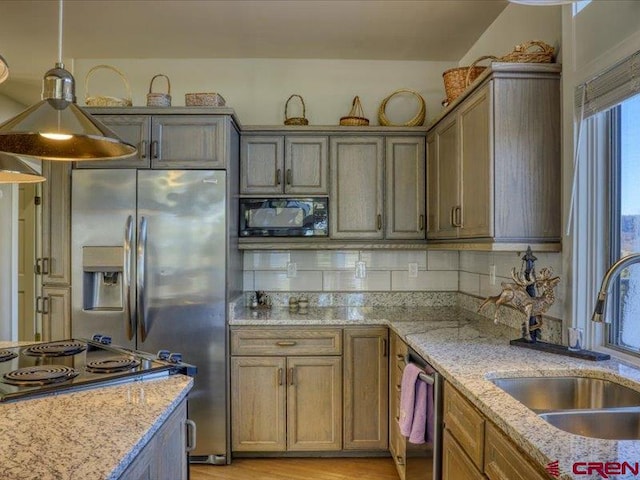 kitchen featuring light hardwood / wood-style floors, sink, light stone counters, appliances with stainless steel finishes, and hanging light fixtures