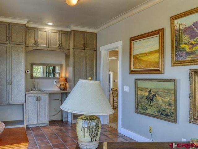 kitchen with dark tile patterned floors, crown molding, and sink