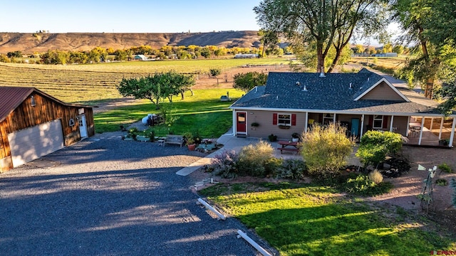 view of front of house featuring a rural view, a front lawn, a garage, a patio area, and a mountain view