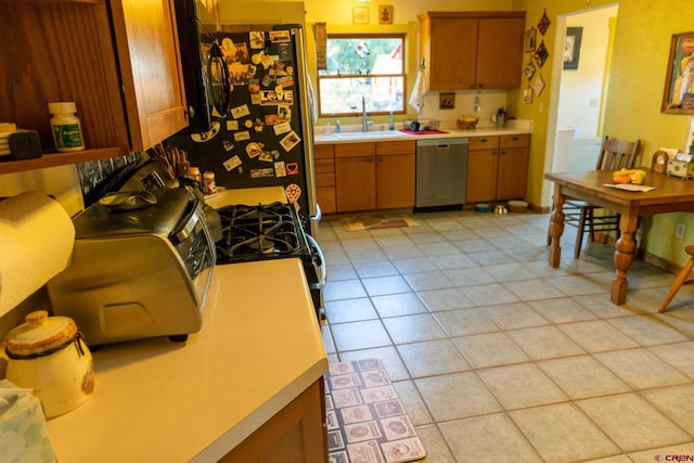 kitchen with stainless steel dishwasher, light tile patterned flooring, black refrigerator, and sink