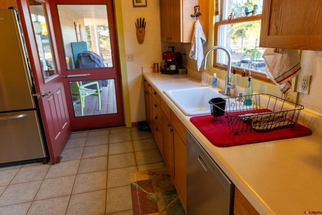 kitchen with a wealth of natural light, appliances with stainless steel finishes, light tile patterned flooring, and sink