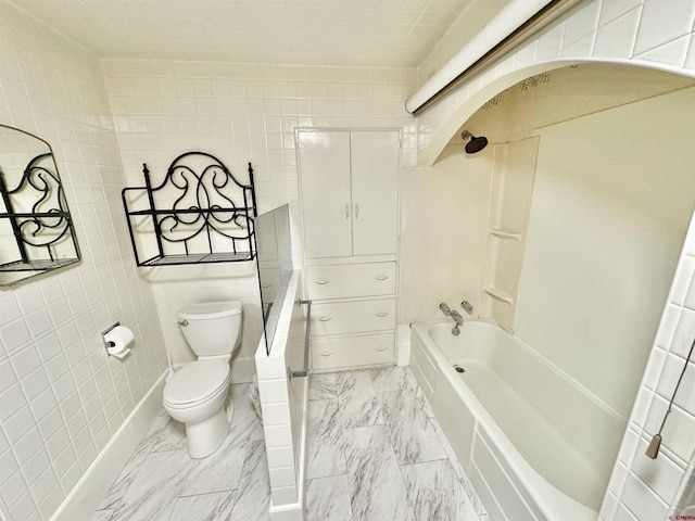 bathroom featuring tile walls, washtub / shower combination, and toilet