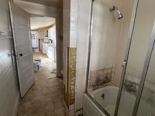 bathroom featuring bath / shower combo with glass door, vanity, and tile walls