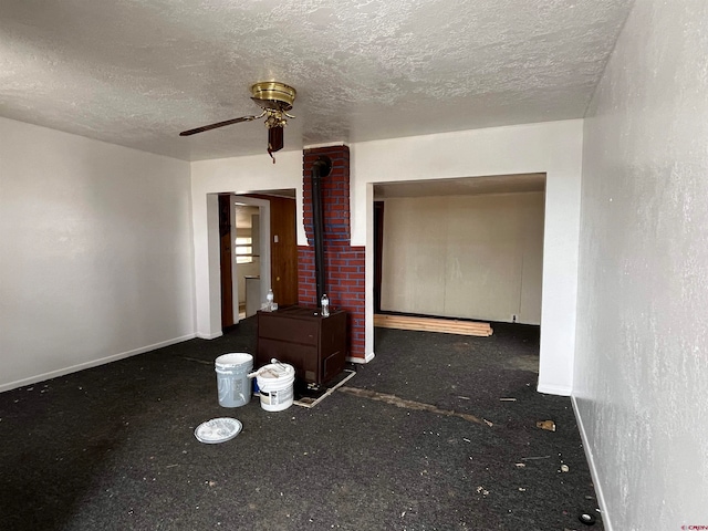 spare room featuring a wood stove, ceiling fan, and a textured ceiling