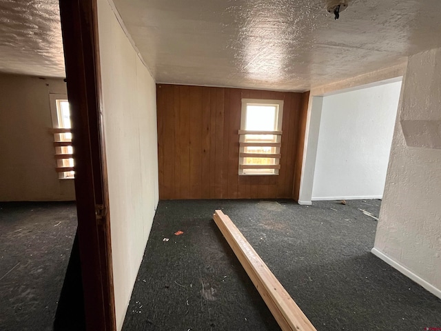 carpeted spare room with wood walls and a textured ceiling