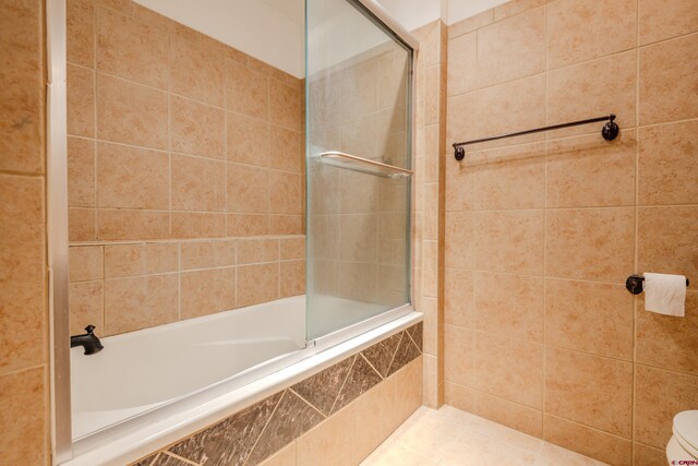 bathroom featuring toilet, tile patterned floors, and shower / bath combination with glass door