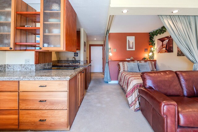 interior space featuring black electric stovetop, light carpet, sink, and light stone countertops