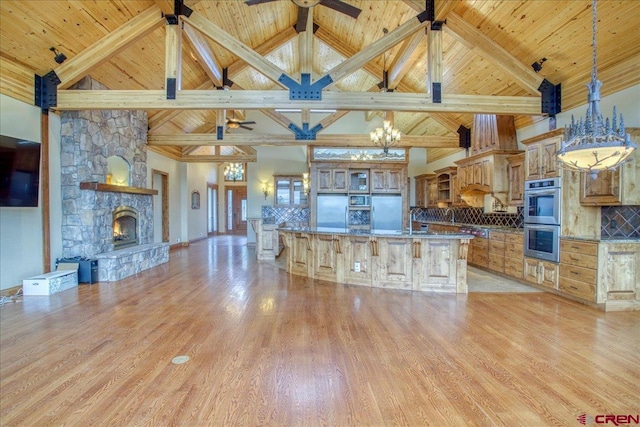 kitchen with stainless steel appliances, a fireplace, backsplash, and high vaulted ceiling