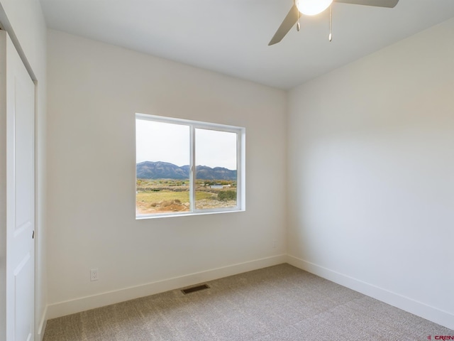 carpeted empty room featuring ceiling fan and a mountain view