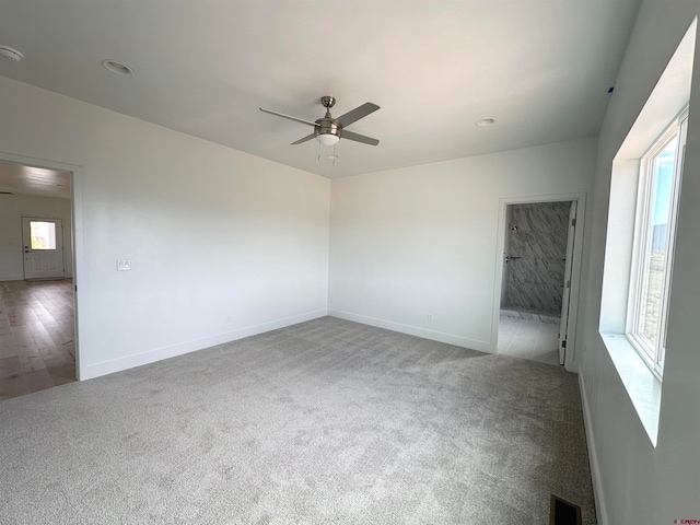 carpeted empty room featuring ceiling fan and plenty of natural light