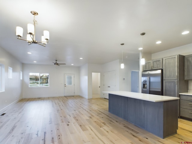 kitchen featuring stainless steel fridge with ice dispenser, a kitchen island, ceiling fan with notable chandelier, and hanging light fixtures