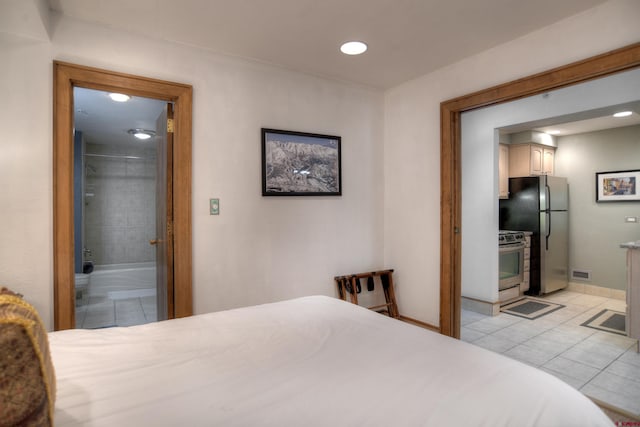 bedroom featuring stainless steel refrigerator, connected bathroom, and light tile patterned floors