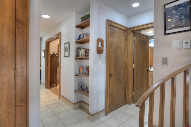 corridor featuring light tile patterned floors and built in shelves