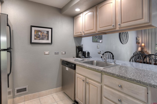 kitchen with stainless steel appliances, light tile patterned floors, sink, and light brown cabinets