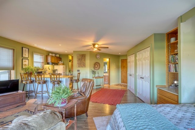 bedroom with ceiling fan, hardwood / wood-style floors, two closets, and white fridge