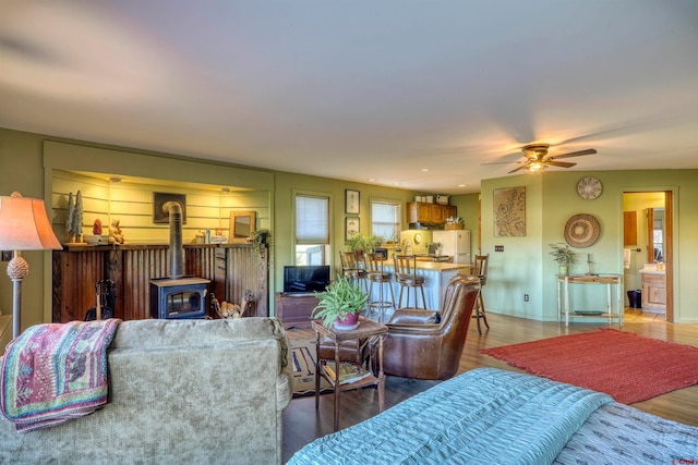 living room with a wood stove, hardwood / wood-style floors, and ceiling fan