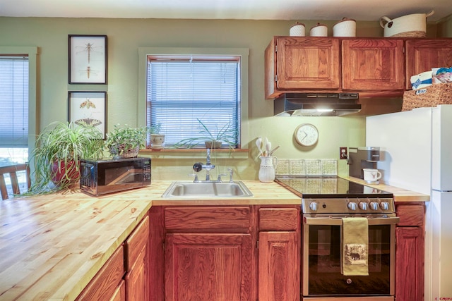 kitchen with butcher block countertops, wood-type flooring, white fridge, electric stove, and sink