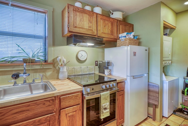 kitchen with light tile patterned flooring, high end range, white refrigerator, and sink