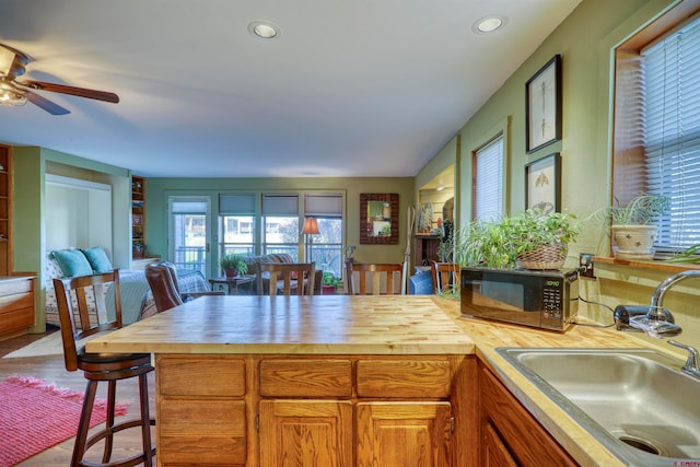 kitchen featuring a kitchen bar, hardwood / wood-style floors, sink, ceiling fan, and wood counters